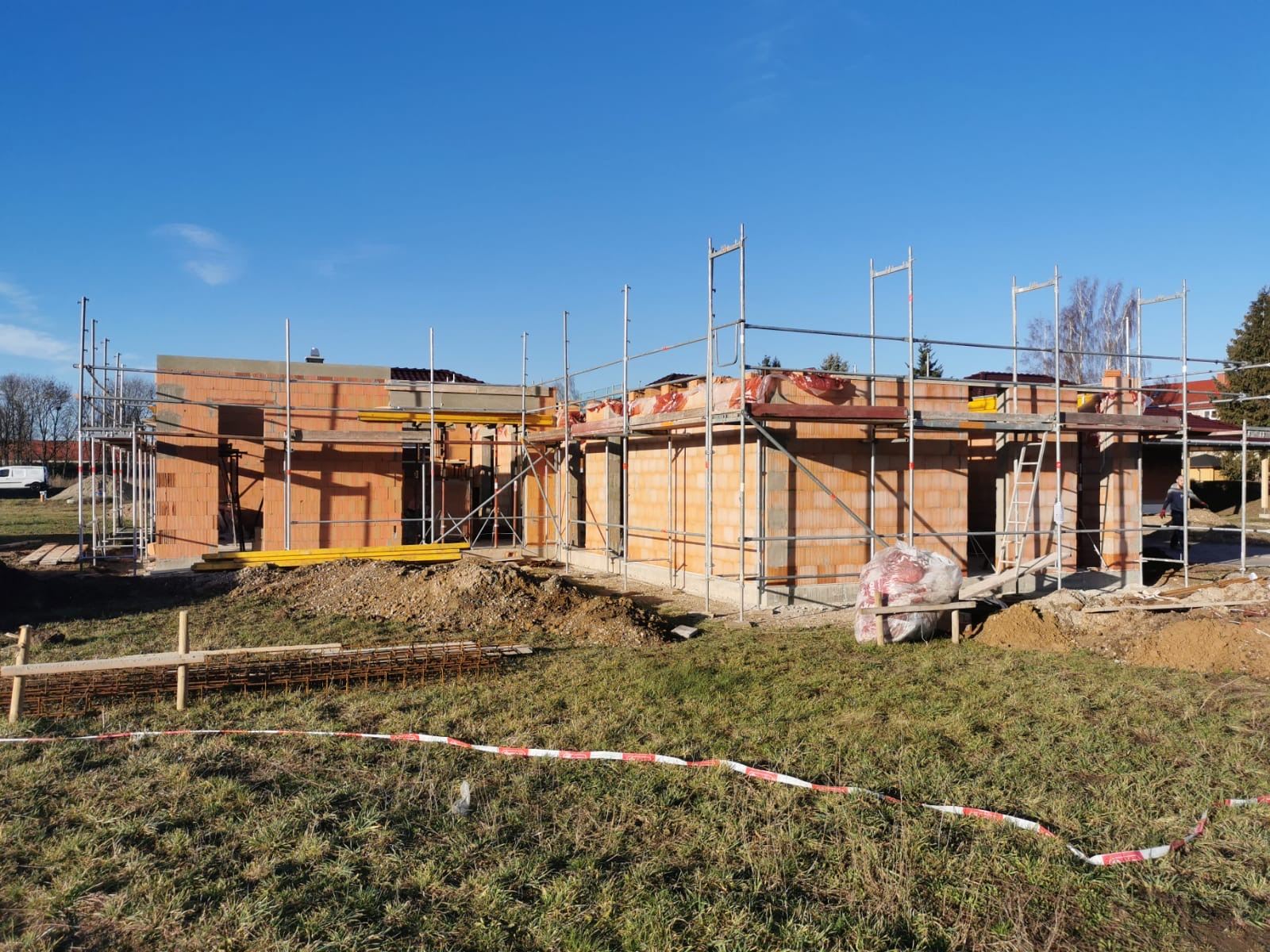 Rohbau eines Bungalows mit Gerüst und Bewehrungsstahl im Vordergrund