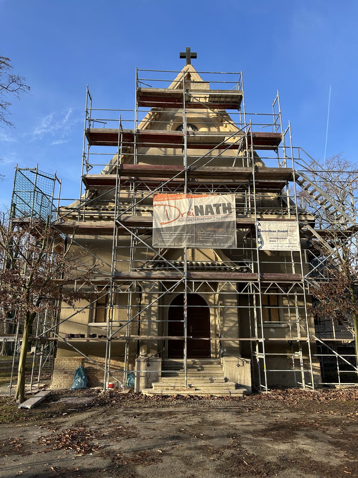 Eingerüstete Kapelle mit Dreinath-Banner während der Sanierung
