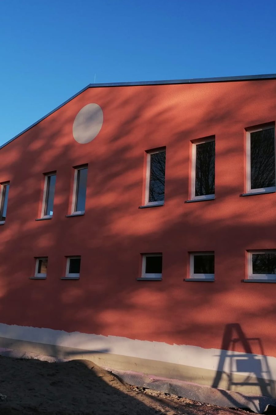 Dasselbe Wohnhaus fertig verputzt in Rot, mit neuen Fensterlaibungen