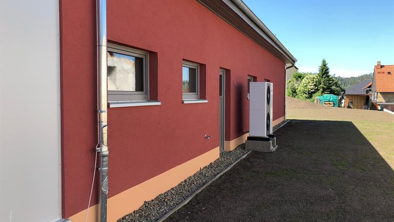 Fertige Außenfassade in rotem Strukturputz mit abgesetztem Sockel