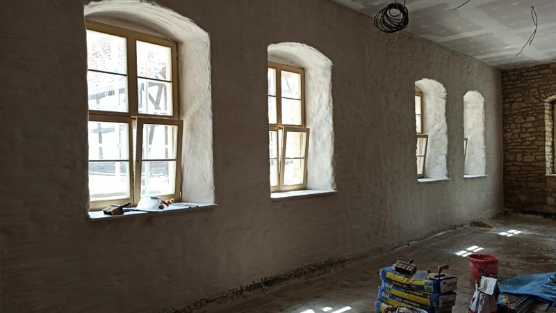 Frisch verputzter Altbauraum mit Rundbogenfenstern