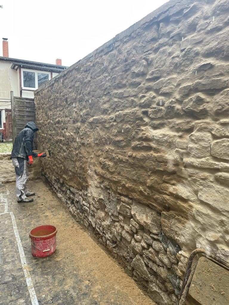 Maurer bei der Instandsetzung einer Natursteinmauer