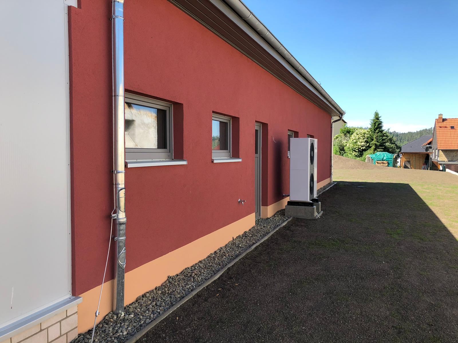 Außenputz an einem Bungalow: rote Strukturfassade mit abgesetztem Sockel