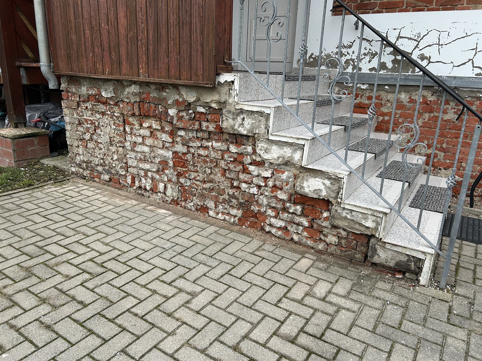 Sockel eines Wohnhauses mit abgeplatztem Putz und mürbem Ziegelmauerwerk